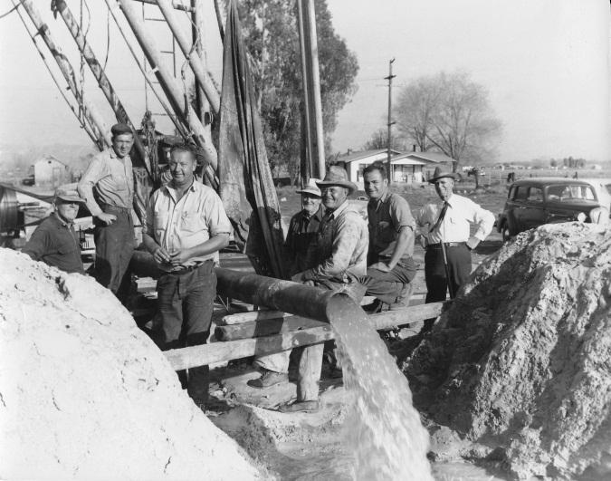 Men gathered around water drilling rig.